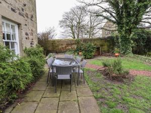 uma mesa e cadeiras no jardim de uma casa em Avocet Cottage em Bamburgh