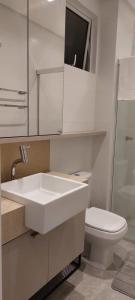 La salle de bains blanche est pourvue d'un lavabo et de toilettes. dans l'établissement Apartamento Studio Hub Smart, à Criciúma
