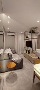 a room with two beds and a table and a tv at Apartamento Studio Hub Smart in Criciúma