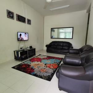 a living room with a leather couch and a television at HOMESTAY MURAH MELAKA Melayu Sahaja in Melaka