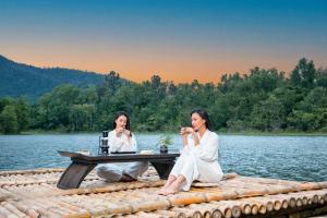 Deux femmes assises à une table de pique-nique sur un lac dans l'établissement The Coffee City - Healing & Retreats, à Buôn Ma Thuột