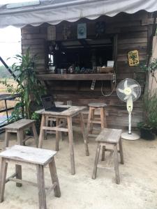 een tafel en vier krukken met een laptop erop bij สวนบ้านนอก in Phayao