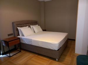 un letto con lenzuola e cuscini bianchi in una stanza di ACACUS LUXURY a Kigali