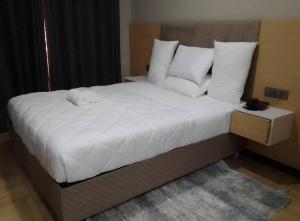- une chambre dotée d'un grand lit avec des draps et des oreillers blancs dans l'établissement ACACUS LUXURY, à Kigali