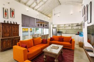 スリ・ジャヤワルダナプラ・コッテにあるAngam Suites Colomboのリビングルーム(オレンジ色のソファ2台、テーブル付)