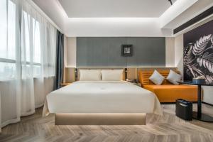 Atour S Hotel Guangzhou Zhujiang Taikoocang في قوانغتشو: غرفة نوم بسرير كبير وأريكة
