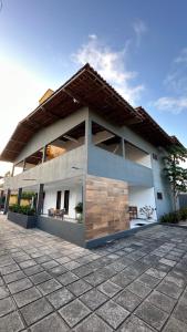 a white building with two benches in front of it at Rio Claro Comfort Hostel e Suítes in São Luís