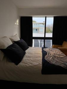 1 dormitorio con cama con almohadas y ventana en Núñez apartment en Buenos Aires