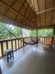 a porch with a hammock and a bench on it at River Point Hostel in Puerto Maldonado