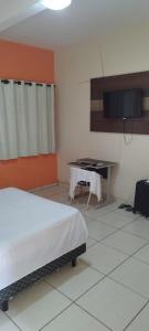 a room with a bed and a table in it at POUSADA ACONCHEGO HOTEL in Imperatriz