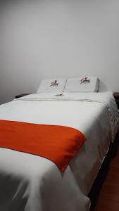Una gran cama blanca con una manta naranja. en GOLDEN PARIS Hotel, en Ayacucho