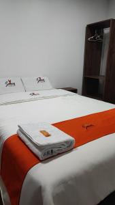een wit bed met oranje en witte handdoeken erop bij GOLDEN PARIS Hotel in Ayacucho