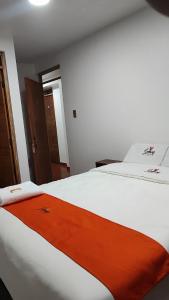 eine orangefarbene Decke auf einem weißen Bett in einem Zimmer in der Unterkunft GOLDEN PARIS Hotel in Ayacucho