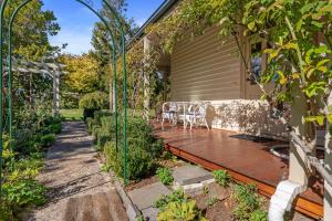 a garden with a deck with chairs on it at Tanglewood House - The Master Suite, Sheffield Tasmania in Sheffield