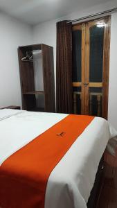 a bedroom with a bed with an orange blanket at GOLDEN PARIS Hotel in Ayacucho