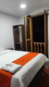 Una cama con una manta naranja y blanca y una ventana en GOLDEN PARIS Hotel, en Ayacucho