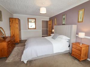 a bedroom with a large white bed and wooden furniture at Beach Cottage in Rhyl