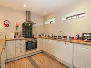 Una cocina con gabinetes blancos y una estufa. en The Garden House, en Chirnside