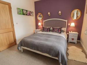 a bedroom with a bed and two night stands and two mirrors at The Garden House in Chirnside