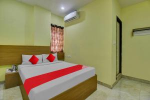 a bedroom with a bed with red pillows and a window at Flagship Hotel Abhi's R Square Near Hayathnagar in Pedda Ambarpet