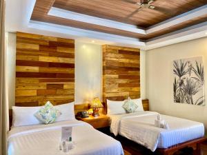 two beds in a room with wooden walls at The Nest El Nido Beach Resort in El Nido