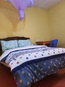 sypialnia z łóżkiem z fioletową kołdrą w obiekcie MAGGY LODGE w mieście Kagio