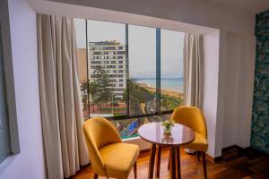 Golden Mar Hotel في ليما: غرفة مع طاولة وكراسي ونافذة كبيرة