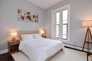 a white bedroom with a large bed and a window at Cozy Downtown Oasis in Hartford
