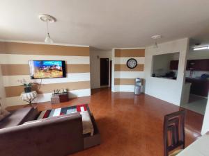 sala de estar con sofá y reloj en la pared en Departamentos de la Costa3, en Machala