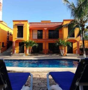 uma piscina em frente a um edifício com duas cadeiras em HDA VALENTINA em Playa del Carmen