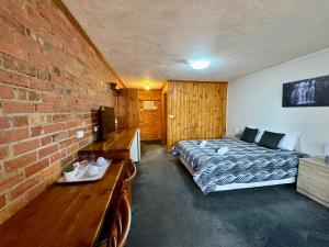 een slaapkamer met een bed en een bakstenen muur bij Diamond House Heritage Restaurant and Motor Inn in Stawell