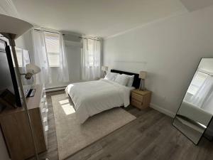 a white bedroom with a bed and a mirror at Cozy 1BR Condo in West Hartford