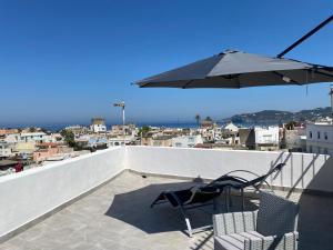un patio avec deux chaises et un parasol sur le toit dans l'établissement La fortezza, à Ischia