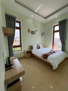 a bedroom with a large bed and two windows at Alex Home Đà Lạt in Da Lat