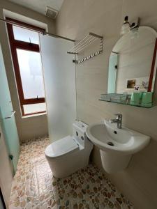 a bathroom with a sink and a toilet and a mirror at Alex Home Đà Lạt in Da Lat