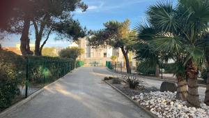 una strada vuota con palme e un edificio di BEGOOD'IZ naturiste Studio indépendant au calme au coeur du village a Cap d'Agde