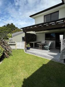 uma casa com um pátio com uma mesa e cadeiras em Coastal Golf & Spa Guesthouse em Mount Maunganui