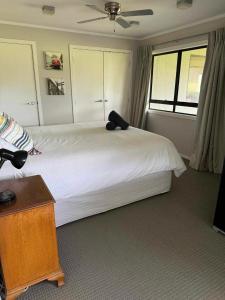 a bedroom with a white bed with a black pillow on it at Coastal Golf & Spa Guesthouse in Mount Maunganui