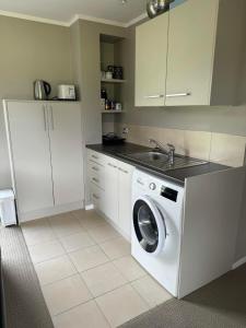 eine Küche mit einer Waschmaschine und einem Waschbecken in der Unterkunft Coastal Golf & Spa Guesthouse in Mount Maunganui