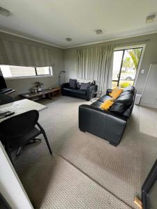 sala de estar con sofá negro y mesa en Coastal Golf & Spa Guesthouse, en Mount Maunganui