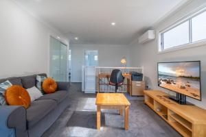 a living room with a couch and a flat screen tv at Shell Cove Escape in Shellharbour