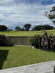 a garden with a fence and a field with trees at Coastal Golf & Spa Guesthouse in Mount Maunganui