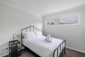 um quarto branco com uma cama e uma janela em Shell Cove Escape em Shellharbour mais 15 fotografias