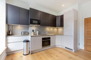 a kitchen with white counters and black cabinets at Fitzrovia & Soho - 3BR - CityApartmentStay in London