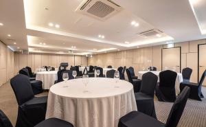 una sala de conferencias con mesas blancas y sillas negras en Sweet May Seogwipo Hotel en Seogwipo