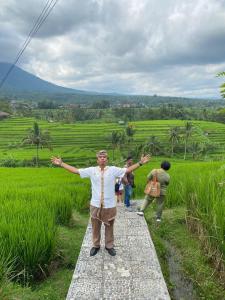 a man standing on a walkway with his arms out at Teras Subak Jatiluwih in Jatiluwih