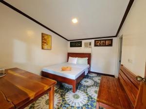 a bedroom with a bed and a table in it at Tambayan Rooms and Cottages by SMS Hospitality in Carmen