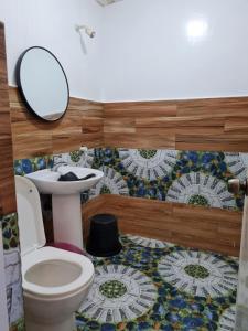 a bathroom with a toilet and a sink and a mirror at Tambayan Rooms and Cottages by SMS Hospitality in Carmen