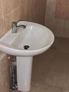 lavabo blanco en un baño alicatado con fosset en Brufut Luxury Villa, en Brufut