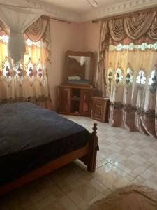 a bedroom with a bed and a mirror and curtains at Brufut Luxury Villa in Brufut